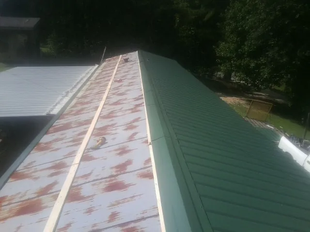 Old rusted panels beside newly installed green metal roofing — Wind Damage Roof Repair by Roofing Brothers in Bethpage