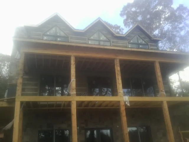 Dormers and porch framing on a large log home under construction — Roof Coating work by our crew in Bethpage